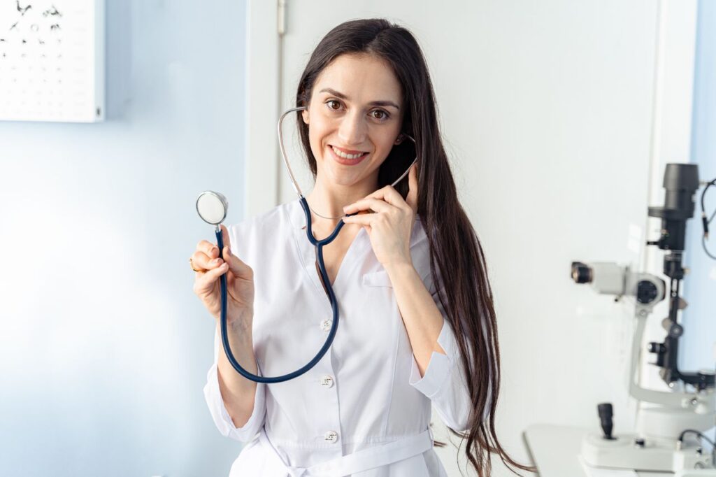 Confident female doctor holding a stethoscope while smiling in a clinic setting.